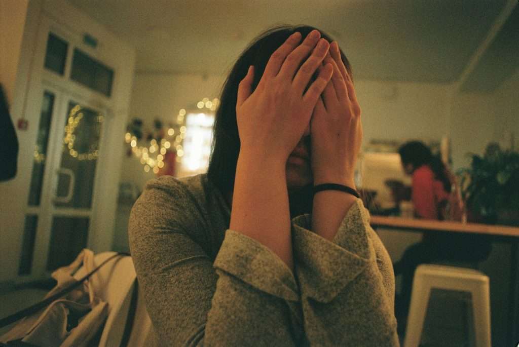 girl with hands over face overwhelmed